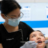 Dentist operating on patient answering can i brush my teeth after wisdom tooth removal