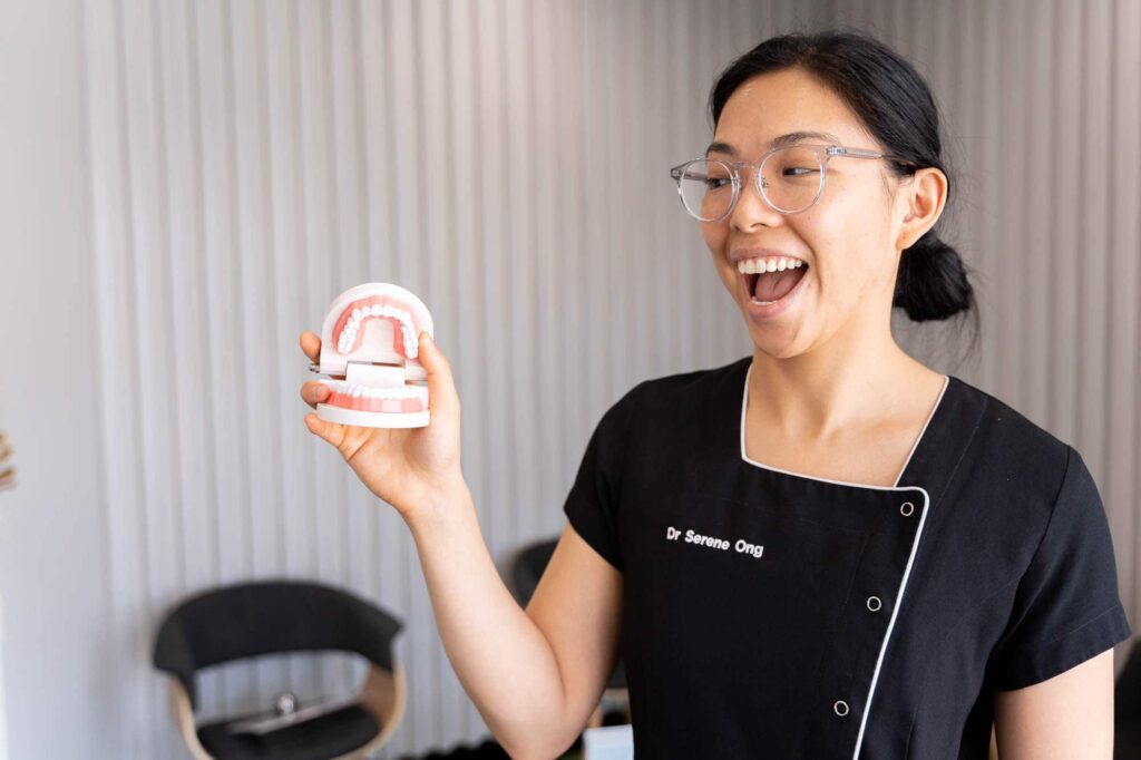Dentist Dr Serene Ong holding tooth model to demonstrate how tooth sensitivity can appear